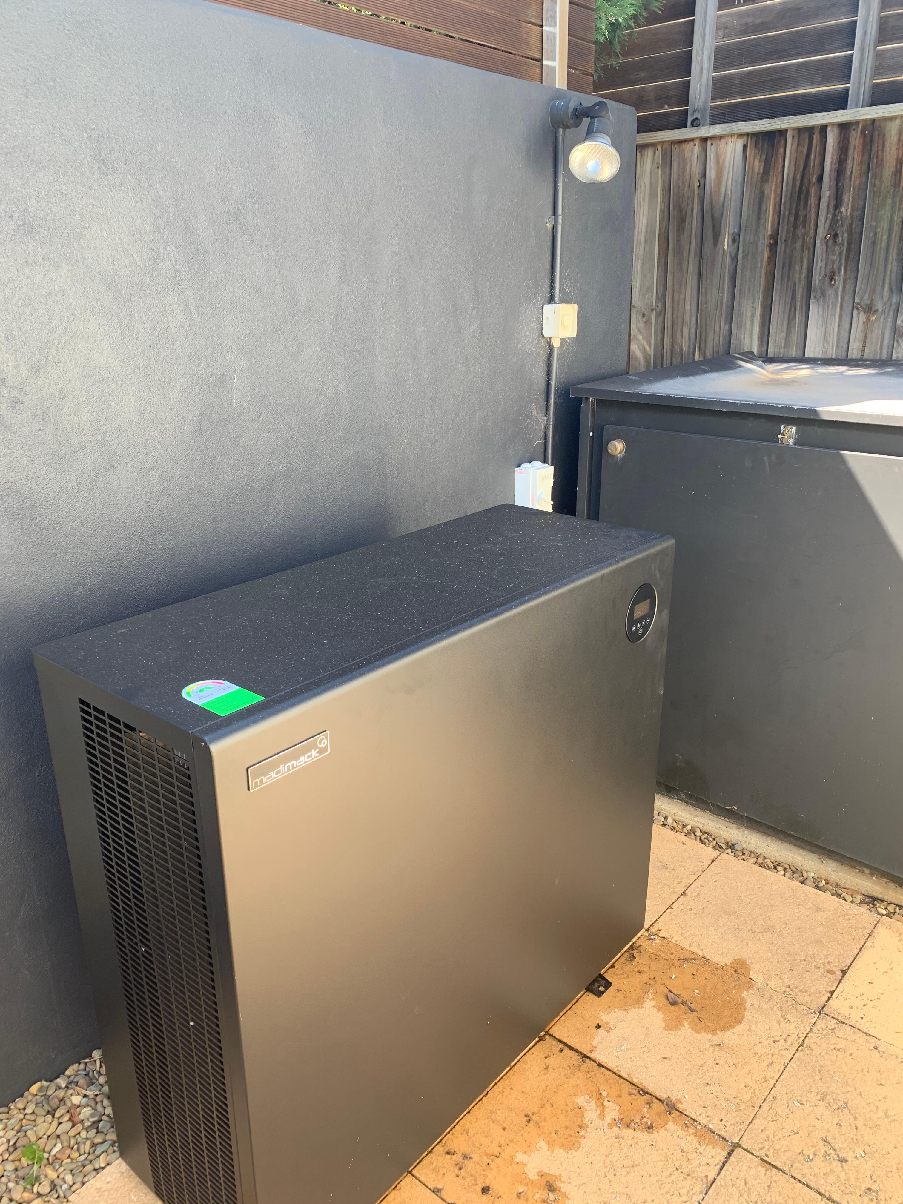 Madimack pool heat pump installed beside a home